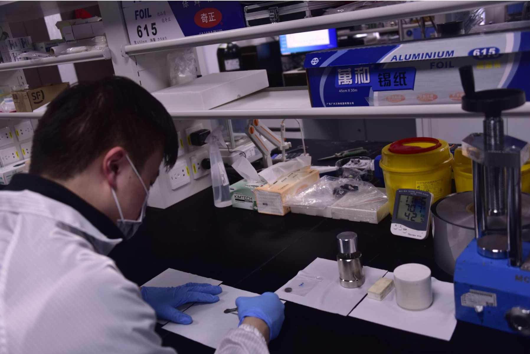 A photo that shows a scientist in a laboratory working at a bench and holding a small sample with tweezers.